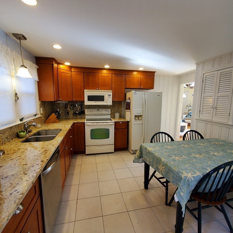 45 Nipigon Way West Dennis, MA 02639 - Photo 14 of 42 a kitchen with stainless steel appliances granite countertop a table chairs sink refrigerator and microwave