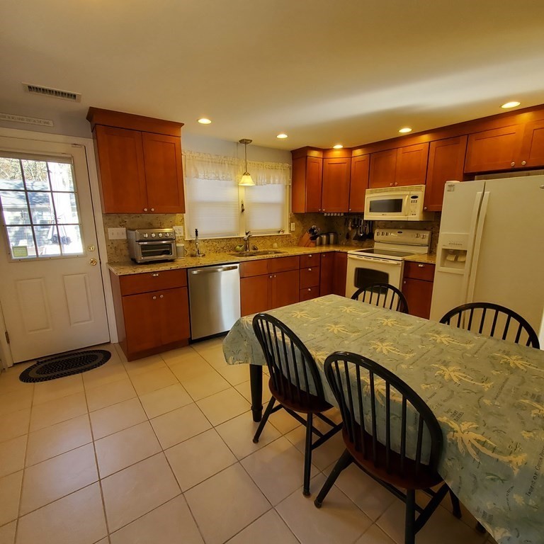 45 Nipigon Way West Dennis, MA 02639 - Photo 15 of 42 a kitchen with stainless steel appliances granite countertop a stove a sink a dining table and chairs