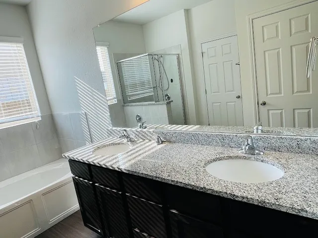 a bathroom with a granite countertop sink a mirror and a bathtub