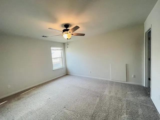 an empty room with windows and chandelier fan