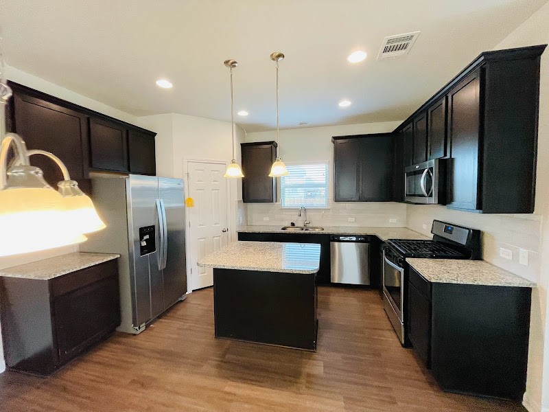 4012 Birdwatch Loop, Unit 8 Pflugerville, TX 78660 - Photo 6 of 23 a large kitchen with stainless steel appliances wooden cabinets a refrigerator and a stove top oven