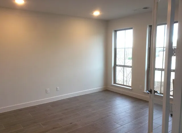 a view of an empty room with wooden floor and a window