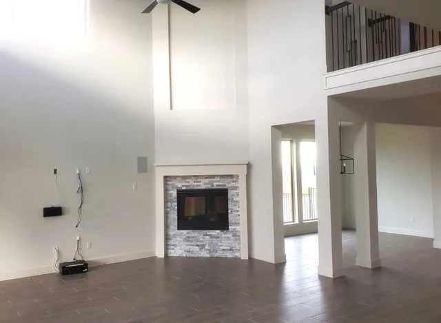 a view of an empty room with wooden floor and a fireplace