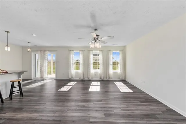 a view of an empty room with window and wooden floor