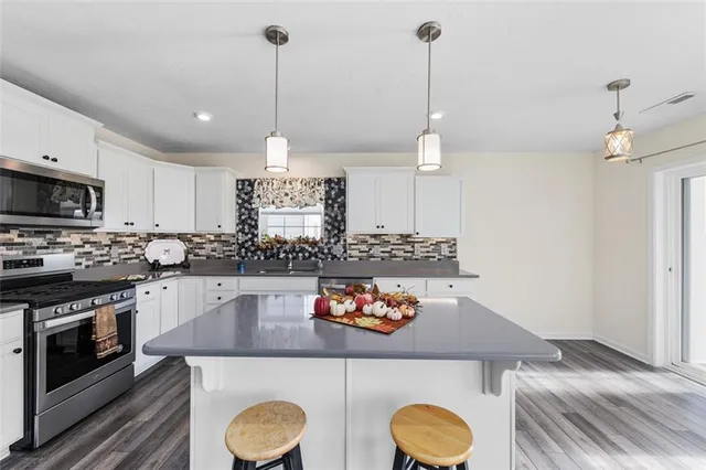 a kitchen with stainless steel appliances granite countertop a sink a stove and a wooden floors