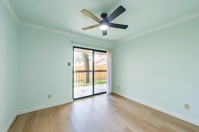an empty room with wooden floor and ceiling fan