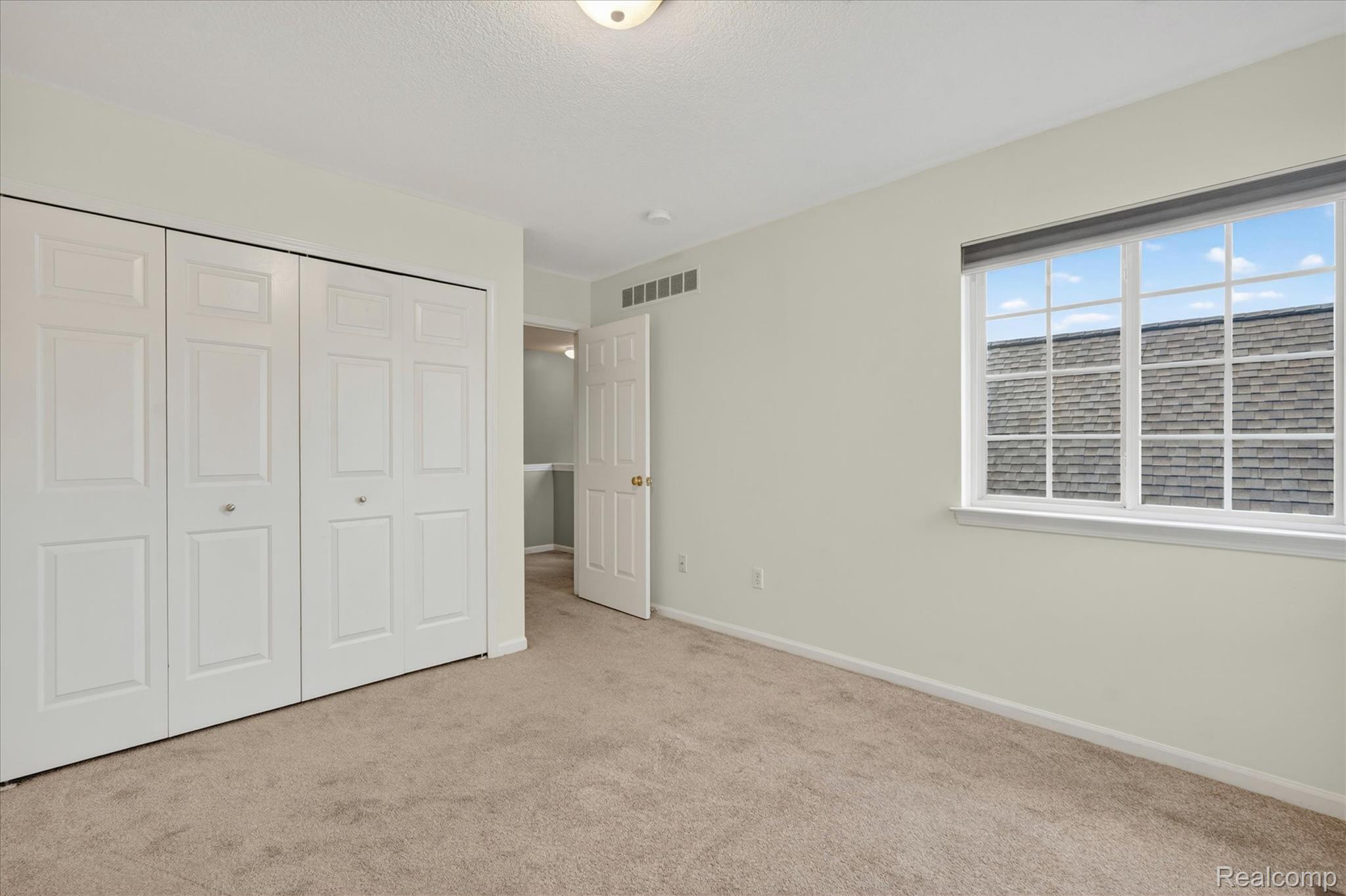 456 Lilly View Court Howell, MI 48843 - Photo 19 of 45 Carpeted room with a large window featuring a white grid, light-colored walls, and a ceiling-mounted light fixture