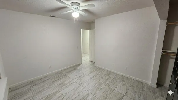 an empty room with wooden floor and fan