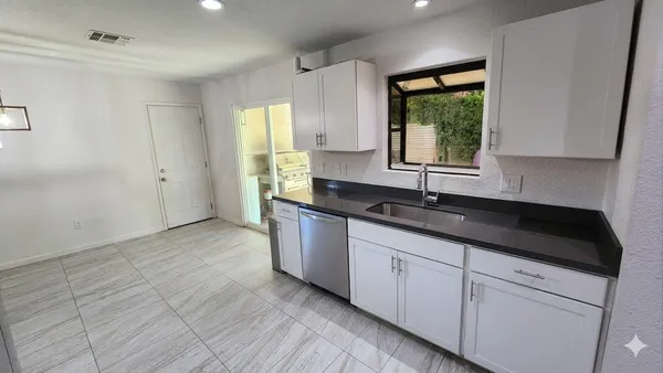 a kitchen with granite countertop a sink and white cabinets