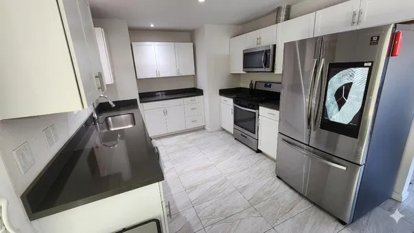 a kitchen with stainless steel appliances a refrigerator a sink and white cabinets