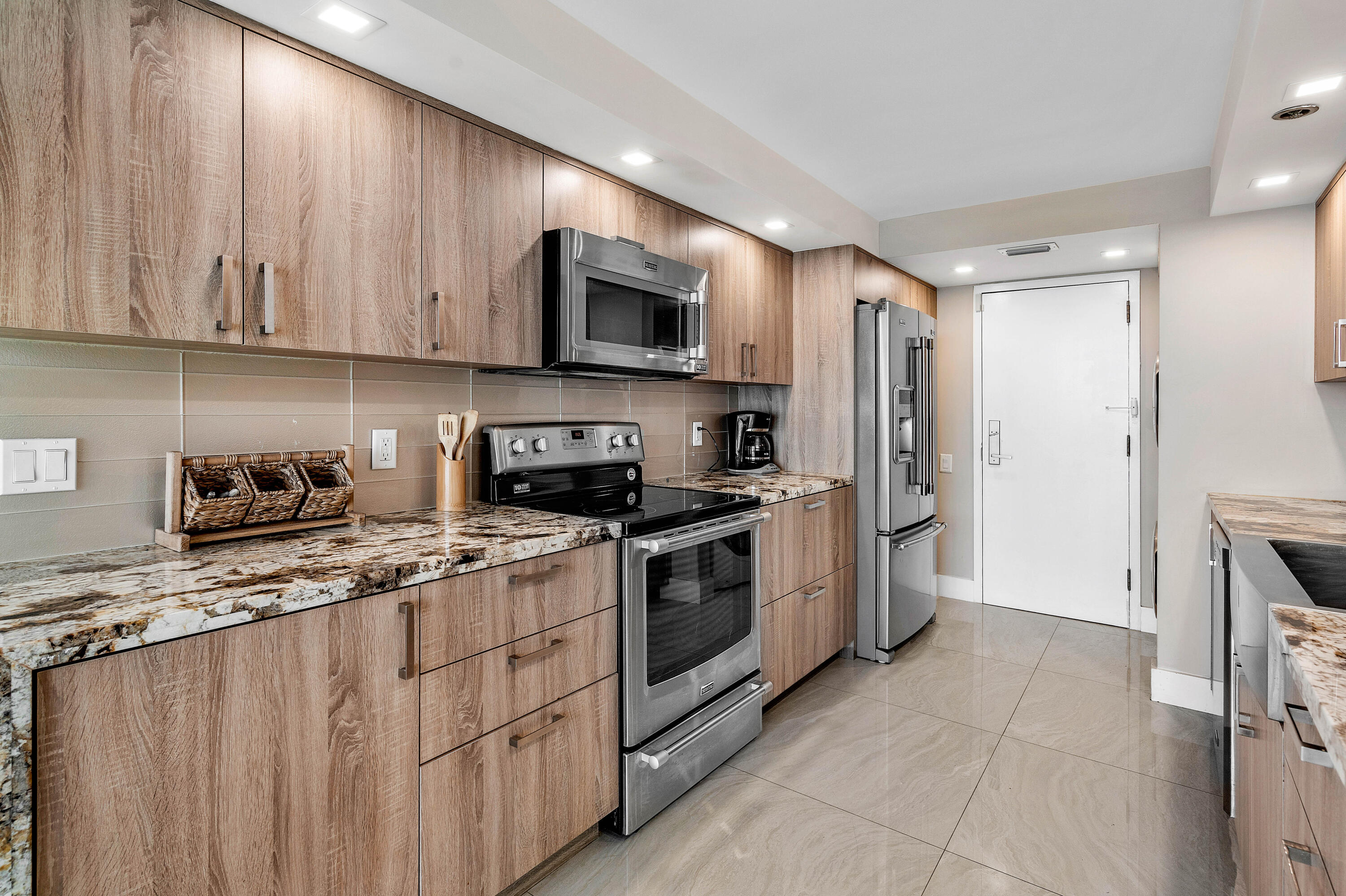 250 South Ocean Boulevard, Unit 7E Boca Raton, FL 33432 - Photo 18 of 45 a kitchen with stainless steel appliances granite countertop a stove a sink and a refrigerator