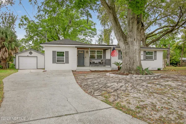 a backyard of a house with potted plants and large tree