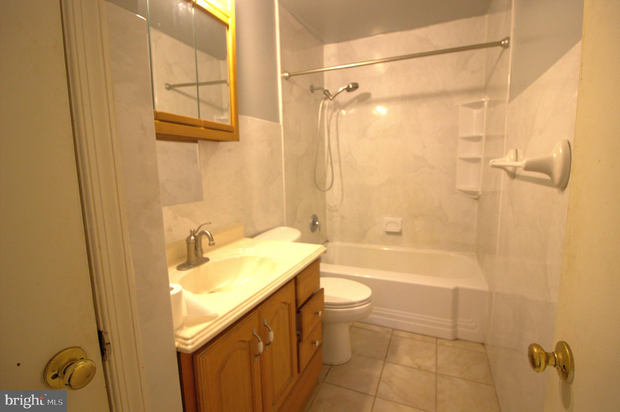 7613 Maple Road Baltimore, MD 21222 - Photo 11 of 32 a bathroom with a granite countertop sink a toilet and shower