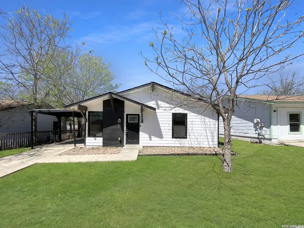 a front view of house with yard and trees in the background