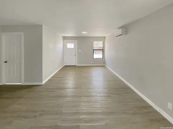 a view of an empty room with window and wooden floor