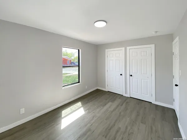 an empty room with wooden floor and windows
