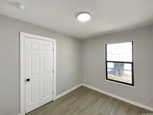 an empty room with wooden floor and windows