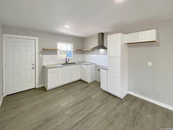 a kitchen with white cabinets and sink