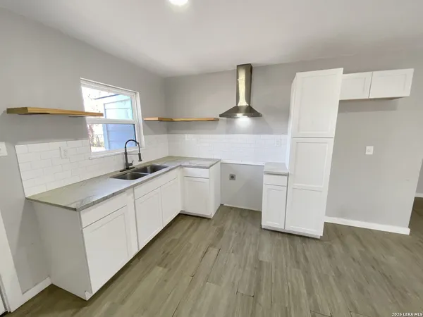 a kitchen with a sink a stove cabinets and wooden floor