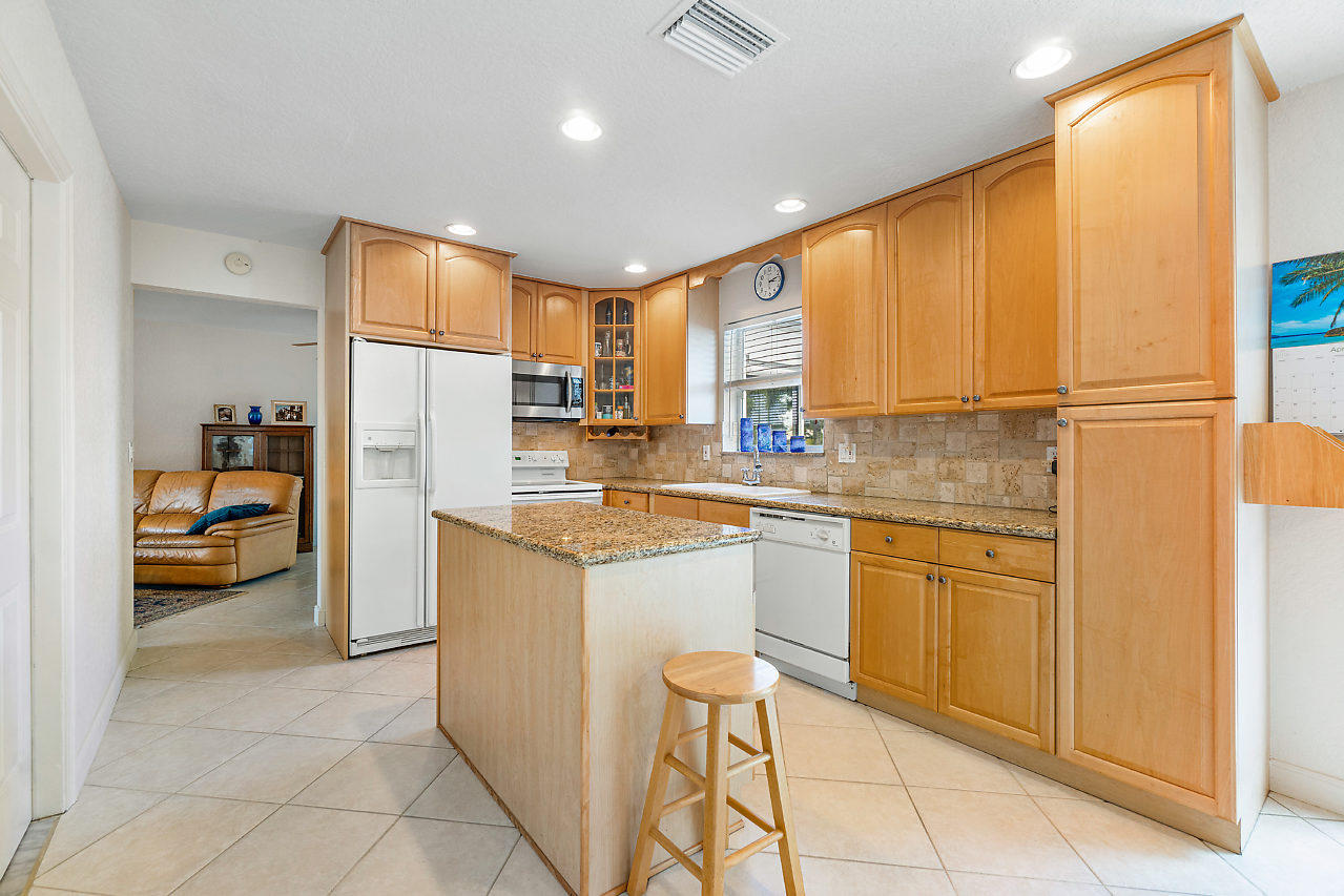10921 Gable Street Boca Raton, FL 33428 - Photo 4 of 28 a kitchen with stainless steel appliances granite countertop a refrigerator a sink and white cabinets