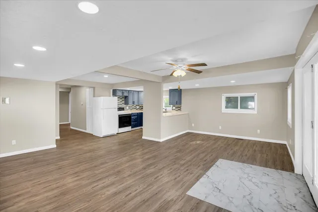 an empty room with wooden floor and kitchen view