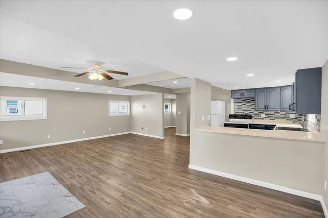 a view of a kitchen with kitchen island a sink wooden floor and black appliances
