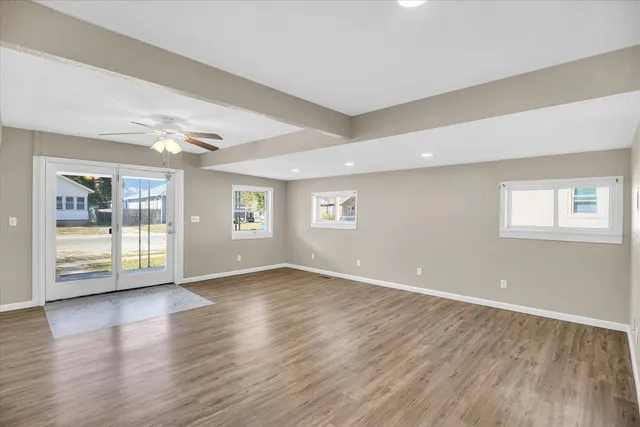 a view of an empty room with wooden floor and a window