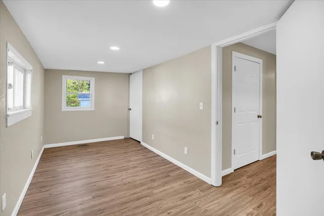 an empty room with wooden floor and windows