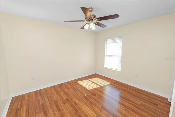 an empty room with wooden floor fan and windows