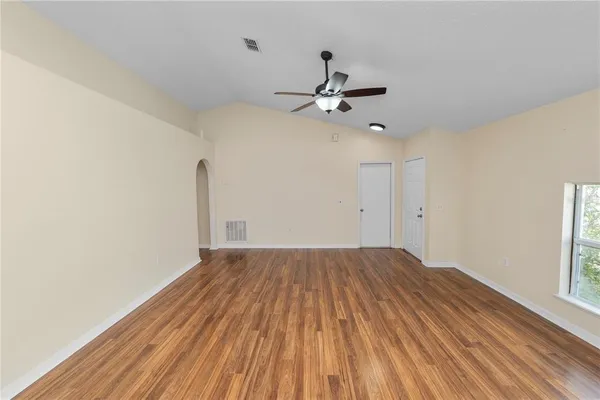 a view of empty room with wooden floor and fan