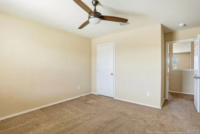 an empty room with ceiling fan and window