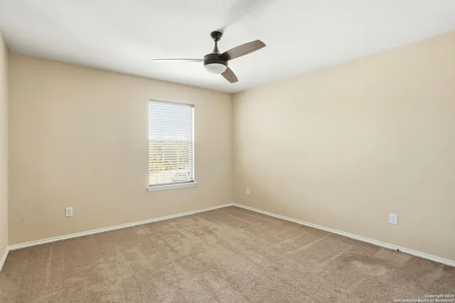 an empty room with a window and a fan