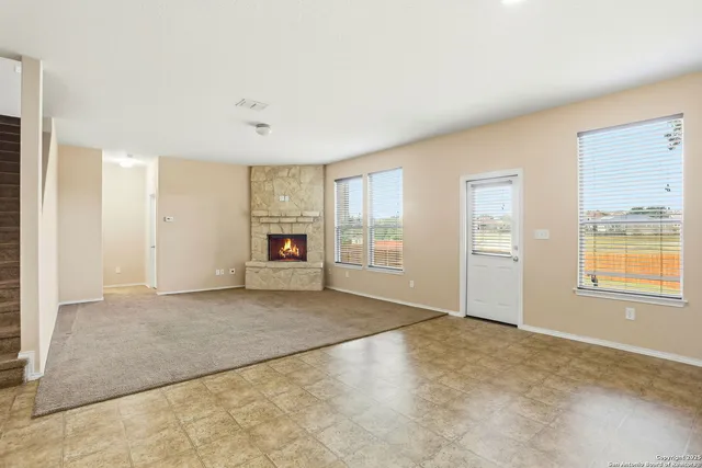 a view of an empty room with a window and fireplace