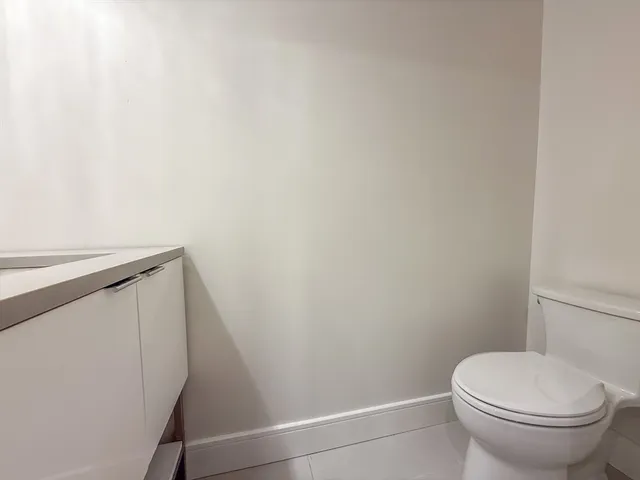 a white toilet sitting next to a white wall