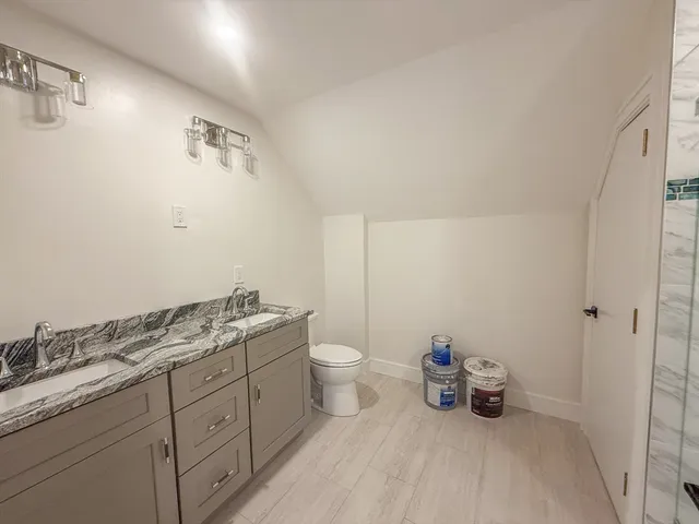 a bathroom with a granite countertop toilet and a sink