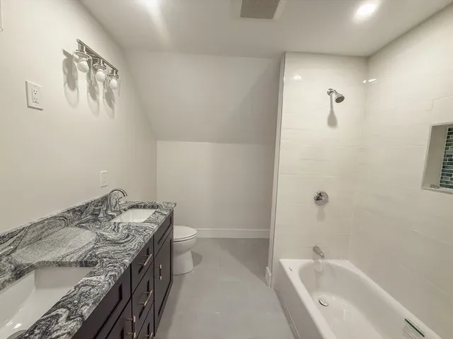 a bathroom with a granite countertop sink a toilet and shower