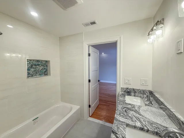 a bathroom with a tub shower and sink