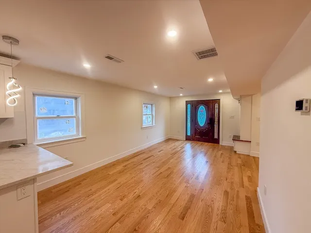 a view of an empty room with wooden floor and a window