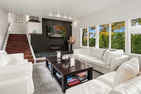 a living room with furniture a flat screen tv and a floor to ceiling window