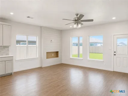 a view of an empty room with a window and wooden floor