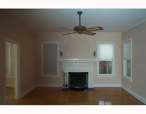 a view of an empty room with wooden floor fireplace and a window