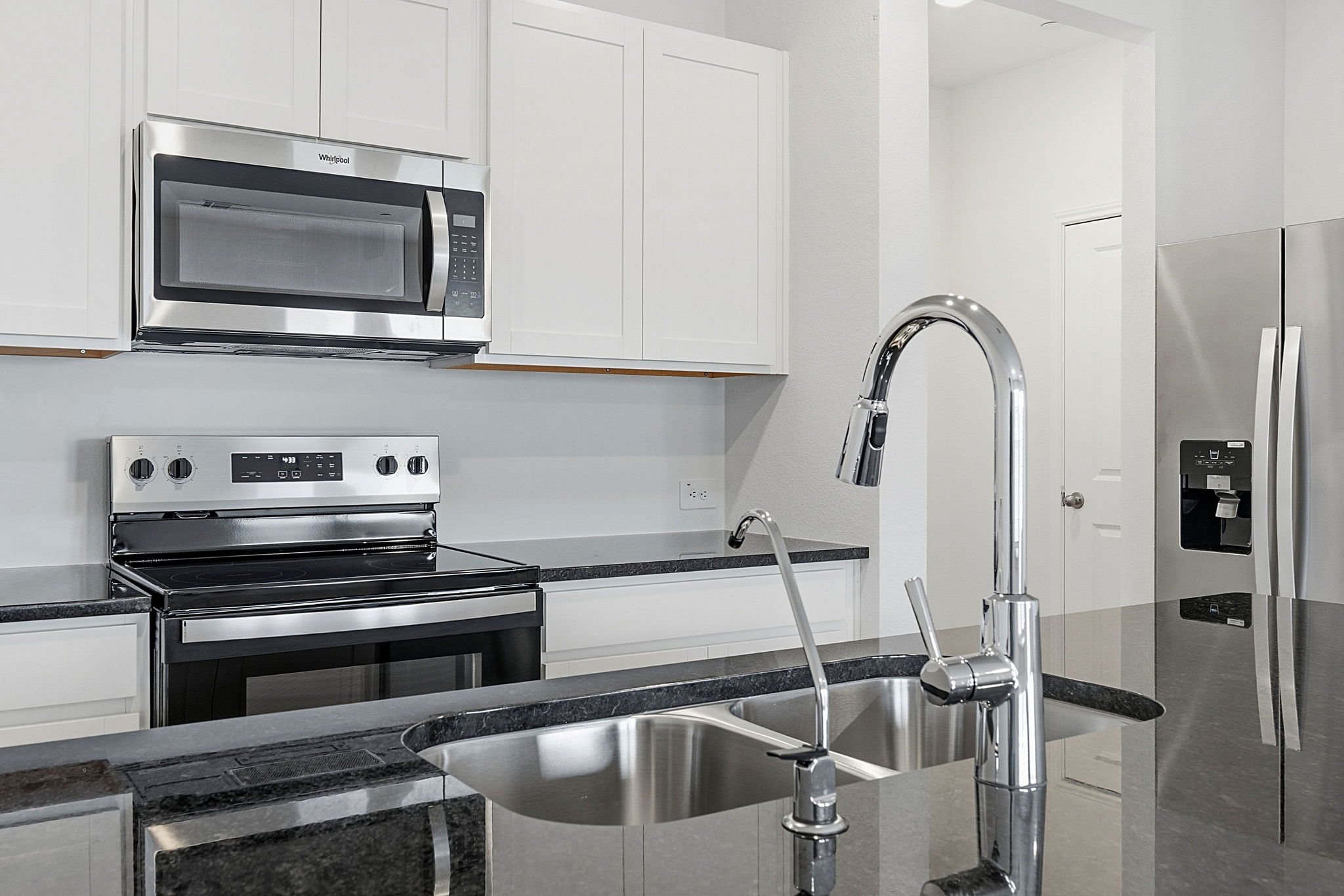 164 Cinnabar Lane, Unit 4 Kyle, TX 78640 - Photo 8 of 23 Stainless steel kitchen appliances, including an over-the-range microwave and electric range, complement dark stone countertops