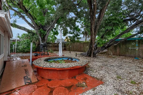 a view of a house with a yard and lawn chairs under a large tree