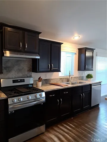 a large kitchen with stainless steel appliances granite countertop a stove a sink dishwasher and a microwave oven on the wooden floor