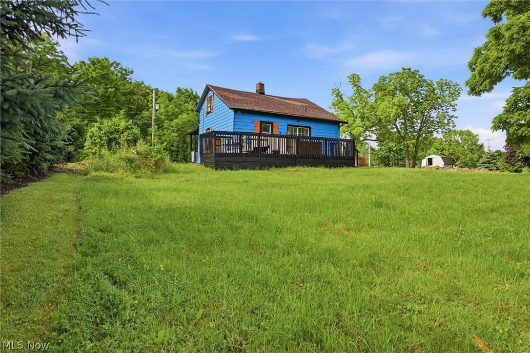 5860 Kirk Road Canfield, OH 44406 - Photo 5 of 17 Expansive green yard with a blue-sided residence featuring a dark-stained deck