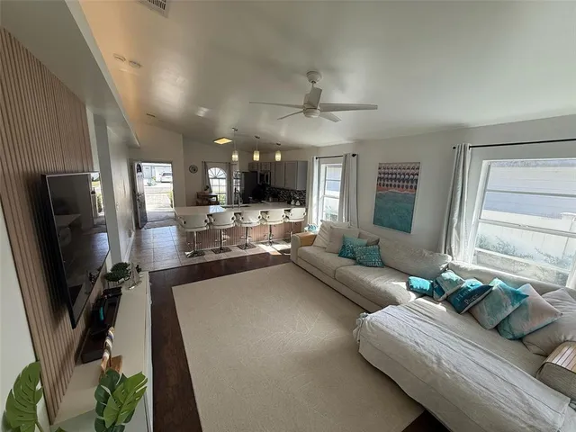 a living room with stainless steel appliances furniture a flat screen tv and a window