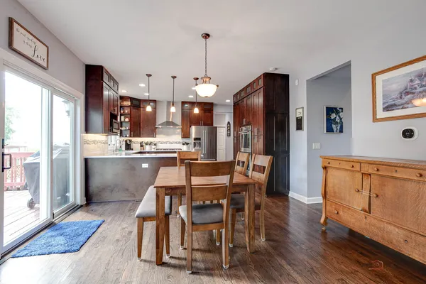 a dining hall with stainless steel appliances kitchen island granite countertop furniture wooden floor and a window