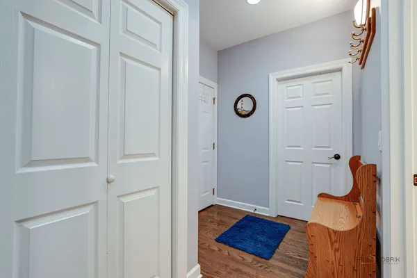 a view of a hallway to a room with wooden floor and front door