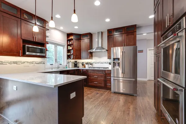 a kitchen with kitchen island a counter top space stainless steel appliances and wooden floor