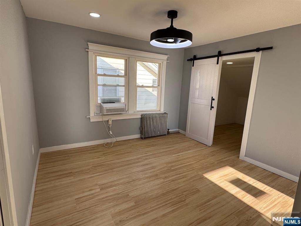 a view of an empty room with window and hardwood floor